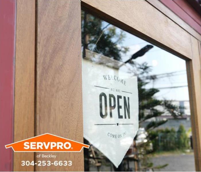 A person places an open for business sign in the storefront window.