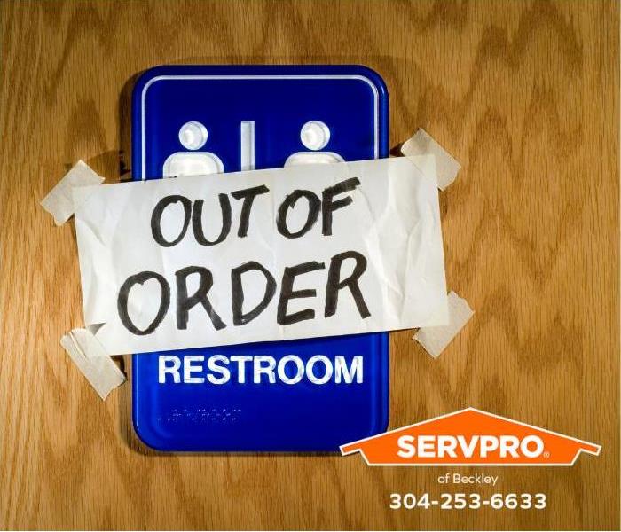 A public restroom sign has an “out of order” notice taped over it.
